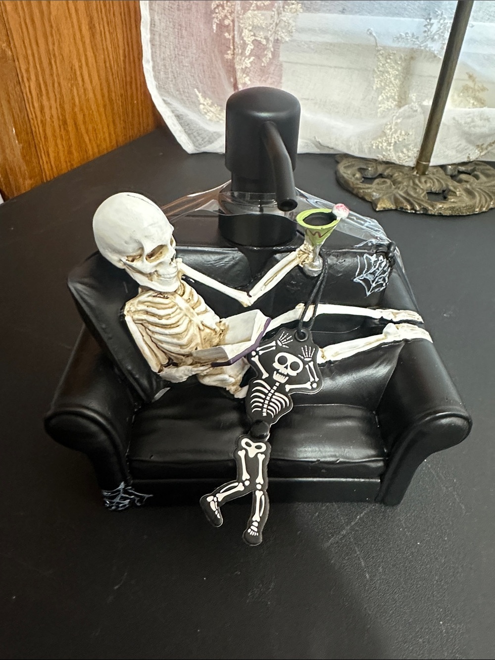 Halloween skeleton reading book and drinking martini on couch soap dispenser